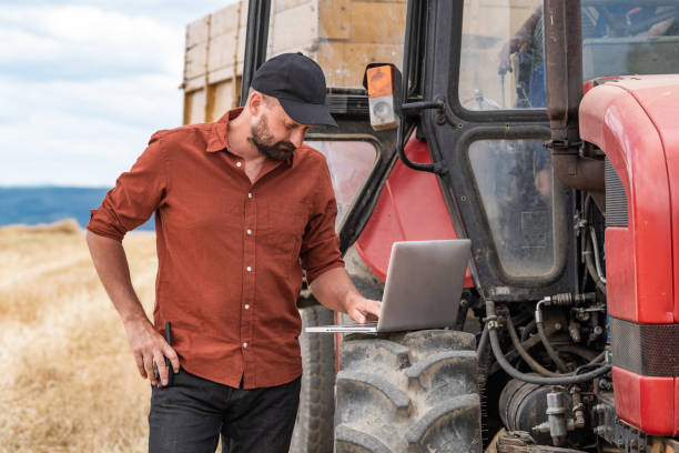 istock Farmer controlled harvest in his field and using laptop 1263111598