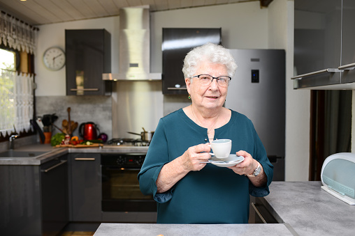 happy senior active woman drinking coffee in a modern kitchen at home