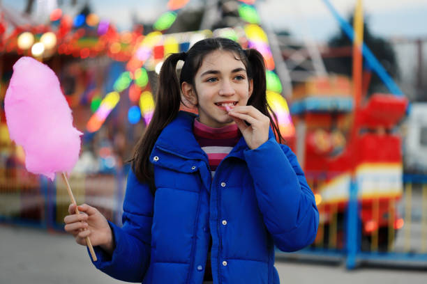 Happy young girl cotton candy in amusement park