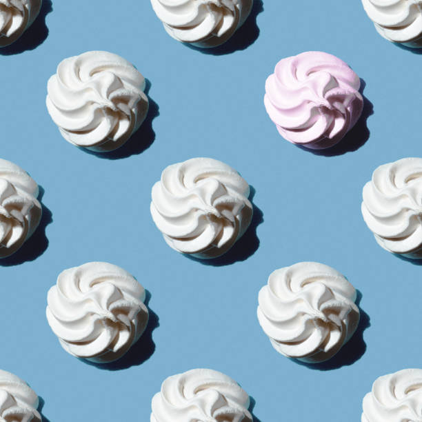 istock Seamless pattern is a white marshmallow or meringue and one pink marshmallow isolated on a classic blue background 1263117851