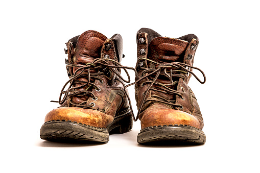 Close-up isolated, men's brown leather worn out work boots on white background,