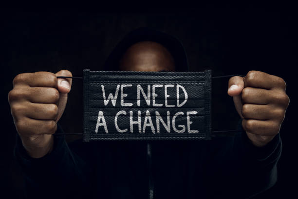 Stop racism Afroamerican man wearing hoodie holds black facial mask with inscription We Need A Change. Anti-racism concept. i cant breathe photos stock pictures, royalty-free photos & images