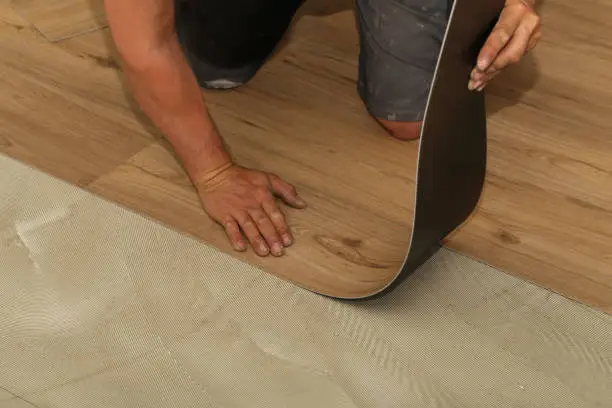 The worker installing new vinyl tile floor.