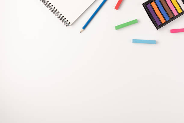 istock Colored wax crayons, sketchbook  on white background. Colorful chalk. Flat lay, top view, copy space. 1263127235