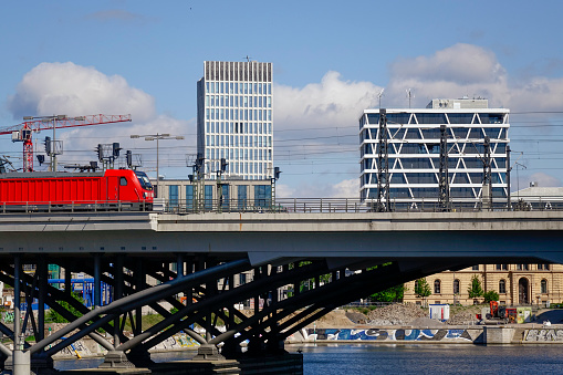 17.05.2020, Berlin, Germany. Railway bridge at the main station of the German capital with outgoing train. In the background are office buildings. The Spree meets the Humboldthafen here.