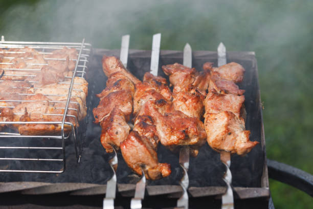 istock grill barbecue meat on a brazier with smoke, green grass background 1263129862