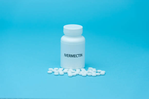 Treatments for Coronavirus (COVID-19): IVERMECTIN in white bottle packaging with scattered pills. Isolated on blue background Treatments for Coronavirus (COVID-19): IVERMECTIN in white bottle packaging with scattered pills. Isolated on blue background. world health organization photos stock pictures, royalty-free photos & images