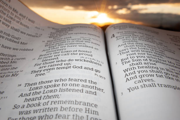 istock Holy Bible open at sunset with highlight on Malachi 4:2. Background with sun and clouds 1263135453