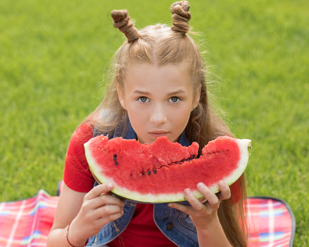 아름다운 빨간 머리 십대 소녀 12 세 와 재미 헤어 스타일 먹는 수박 을 먹는 잔디에 청소년, 여름 시간, 피크닉 야외. 비타민, 영양소. - outdoors child looking at camera 12 13 years 뉴스 사진 이미지