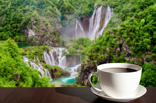 Cup of black coffee or tea with big waterfall background in Croatia