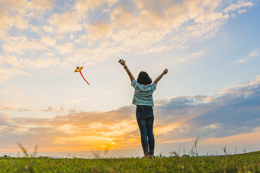 Happy girl running with a kite at sunset outdoors, Little girl running with kite in the field on summer day with sunset.\