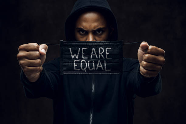 Stop racism Afroamerican man wearing hoodie holds black facial mask with inscription We are equal. Anti-racism concept. i cant breathe stock pictures, royalty-free photos & images