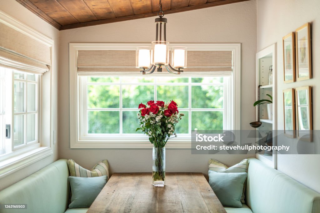 Roses on Rustic Table Comfortable eating nook with roses on rustic table Window Stock Photo