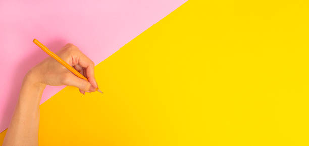 istock The left hand is holding a pencil and is about to write something on a bright pink-yellow background banner. International Left-handers Day on August 13. 1263165599