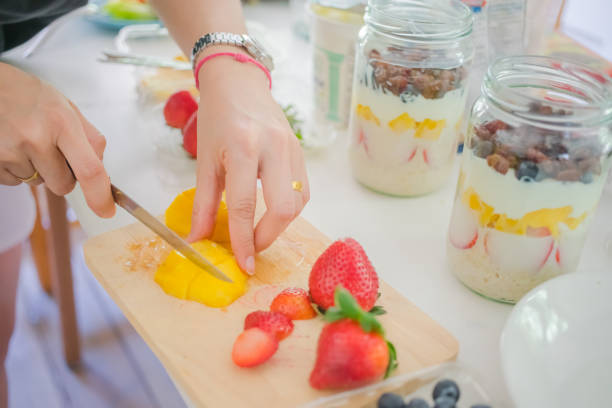 istock Soft focus blur Hand woman slice fruit mango prepare overnight oats menu with yogurt, Oatmeal, strawberries, blueberry on jar healthy food 1263168431