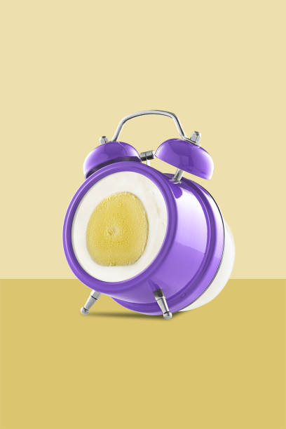 istock Purple alarm clock with an egg instead of a dial on a yellow background, free space for text 1263169571