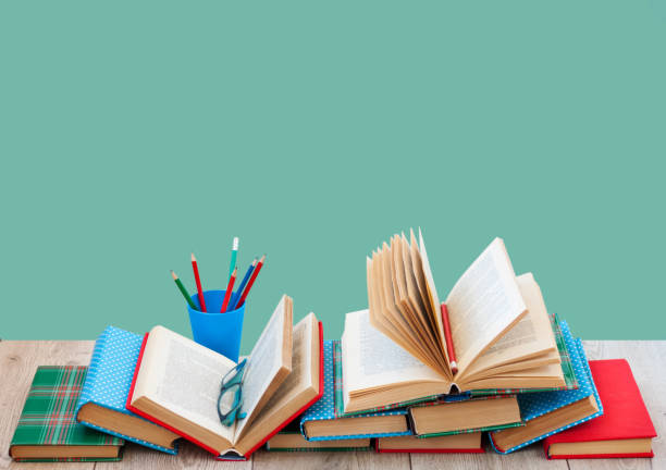 Back to school, pile of books in colorful covers Back to school, pile of books in colorful covers and on wooden table with empty green background. Distance home education.Quarantine concept of stay home classroom empty education desk stock pictures, royalty-free photos & images