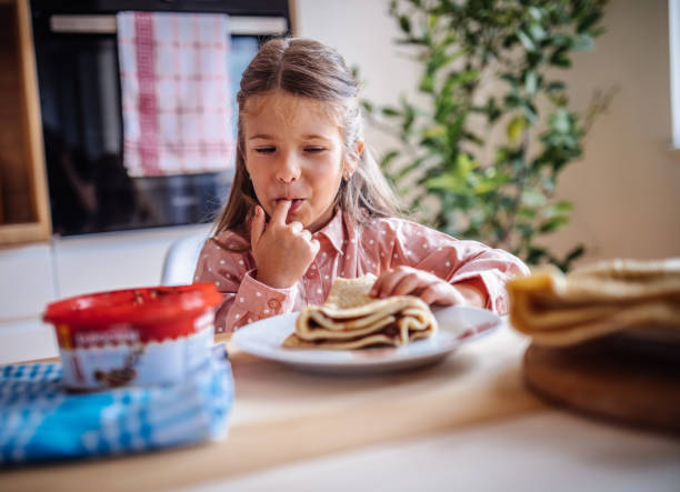 Cute little toddler girl eating homemade fresh crepes or pancakes with chocolate cream Cute little toddler girl eating homemade fresh crepes or pancakes with chocolate cream crepe stock pictures, royalty-free photos & images