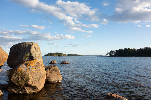 fragment of the Baltic Sea coast with three large granite boulders, against the background of two islands