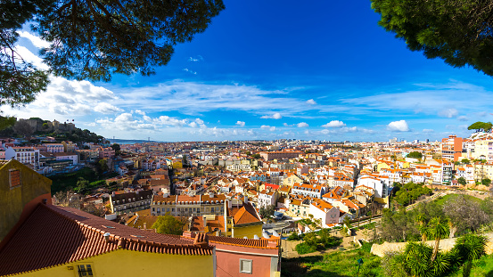 Panoramic view on fast moving clouds in the blue sky over the terracotta rooftops in the centre of Lisbon.