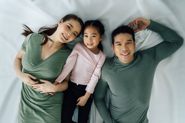 porträt einer fröhlichen asiatischen familie im liegen - women group of people lying down mother stock-fotos und bilder