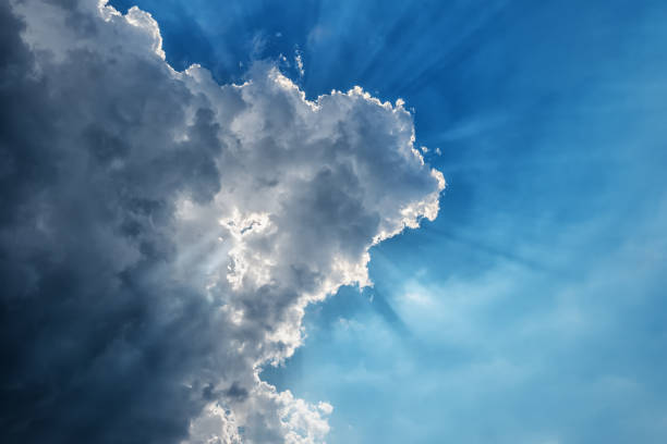 istock Sunbeams through a dark thundercloud in a blue sky 1263179555