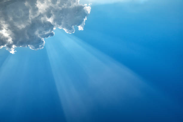 istock Diagonal sunbeam on a blue sky under a cloud in the upper right corner 1263179563