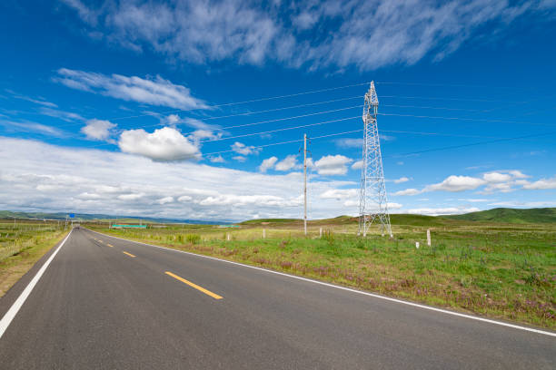 A straight asphalt road under the blue sky and white clouds