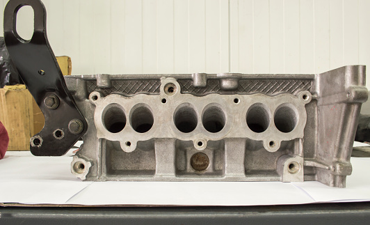 View from the intake manifold on the head of the block of a gasoline three-cylinder internal combustion engine with direct injection, which lies on the desktop