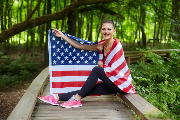 istock attractive girl posing with american flag in forest park 1263214514