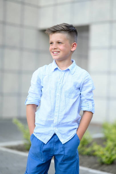 Portrait of happy young boy standing in front of school.