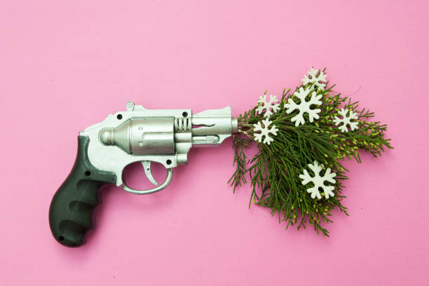 The gun is charged with a winter mood. Toy gun shoots green branches and snowflakes on a pink background. Winter creative concept The gun is charged with a winter mood. Toy gun shoots green branches and snowflakes on a pink background. Winter creative concept Silver Bullet stock pictures, royalty-free photos & images