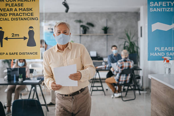 istock Businessman holding document wearing protective face mask at bank 1263229202