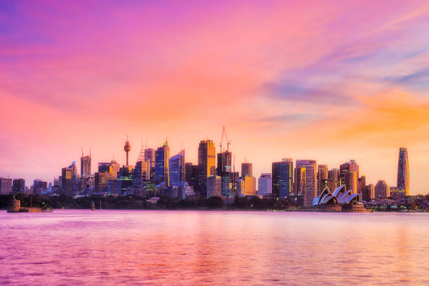 Sy Crem CBD ONly Orange Bright colours of sunset in sky and harbour water in Sydney city of Austalia. sydney skyline sunset stock pictures, royalty-free photos & images