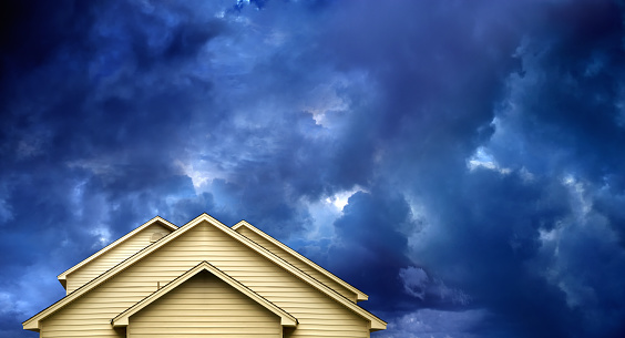 close up rooftop of a wooden house over dramatic sky with storm clouds.