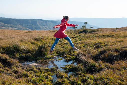 Woman jumping over a puddle