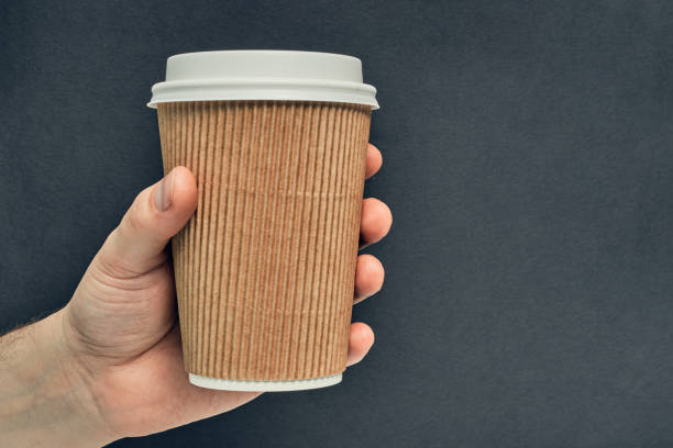 istock Paper cup in hand on a colored background. Eco-friendly materials in a coffee shop, biodegradable disposable tableware. Close up 1263252800