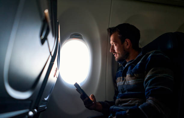 istock Plane passenger looking the plane window and holding and smartphone 1263259295