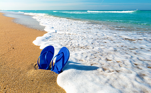 Sandals in the sand on a tropical beach vacation and travel theme