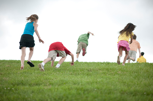 Diverse group of kids running together on a hill.