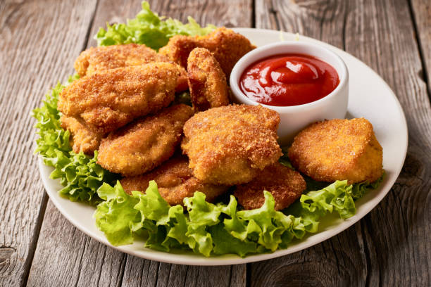istock Close up plate with fried chicken nuggets with lettuce and ketchup 1263294948