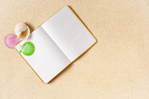 Open empty notebook on sand with sea shells, , summer concept, copy space,