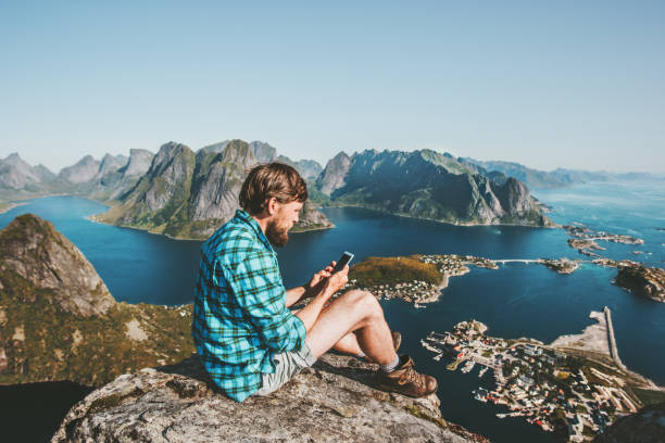 istock Man traveler using smartphone sitting on mountain top 1263324264