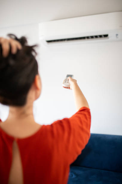 istock Woman switching on air conditioner 1263325972
