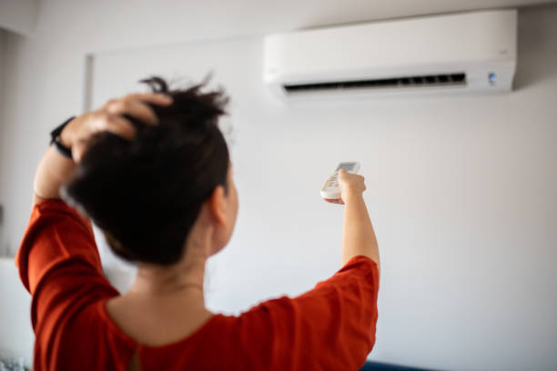Woman switching on air conditioner Woman switching on air conditioner turning on or off photos stock pictures, royalty-free photos & images