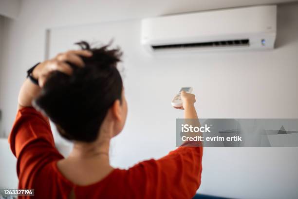 Woman Switching On Air Conditioner Stock Photo - Download Image Now - Air Conditioner, Turning On Or Off, Domestic Life
