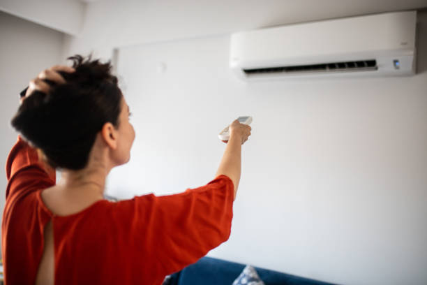 istock Woman switching on air conditioner 1263327223