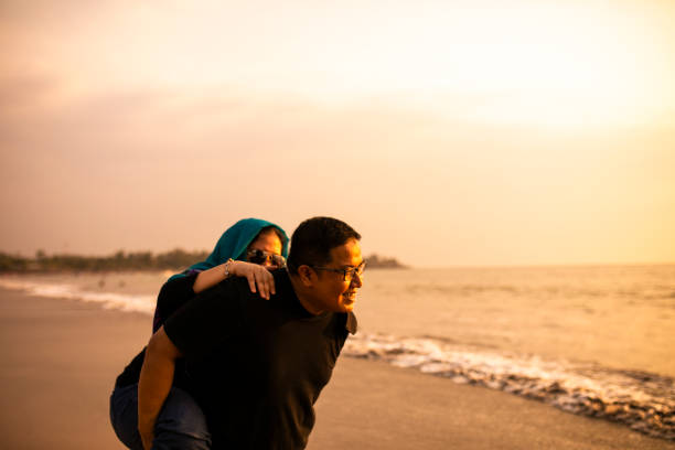 istock man piggyback her wife on the beach 1263329521