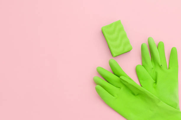 istock Green gloves and a sponge for cleaning on a light pink background. 1263334427