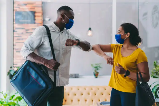 Photo of Business people greeting during COVID-19 pandemic, elbow bump